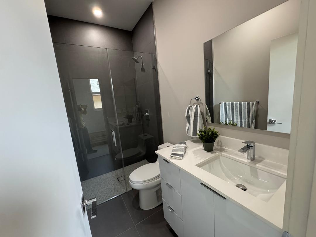 Remodeled bathroom with glass shower, dark finishes and white vanity
