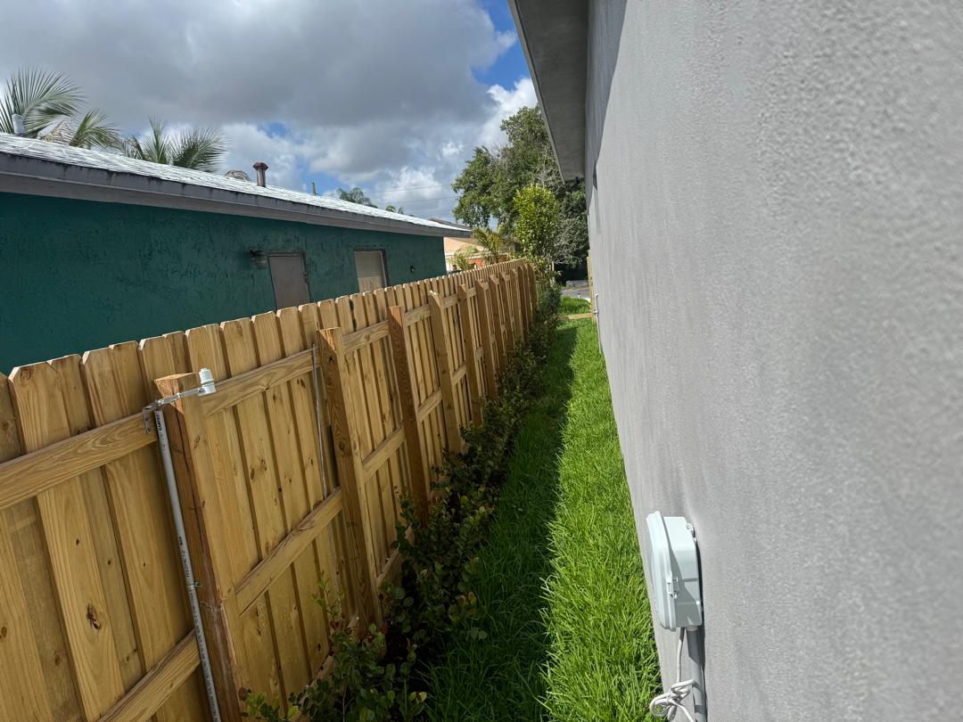 Side view of the finished house with landscaped lawn and wooden fence